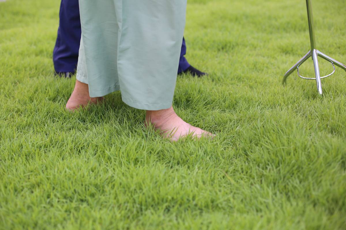 Caring nurse talking with old patient on buffalo grass at homecare visit. Medicine caregiving concept