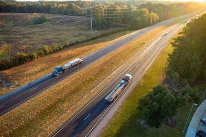 View from above of busy american highway with fast moving trucks and cars. Interstate transportation services concept.